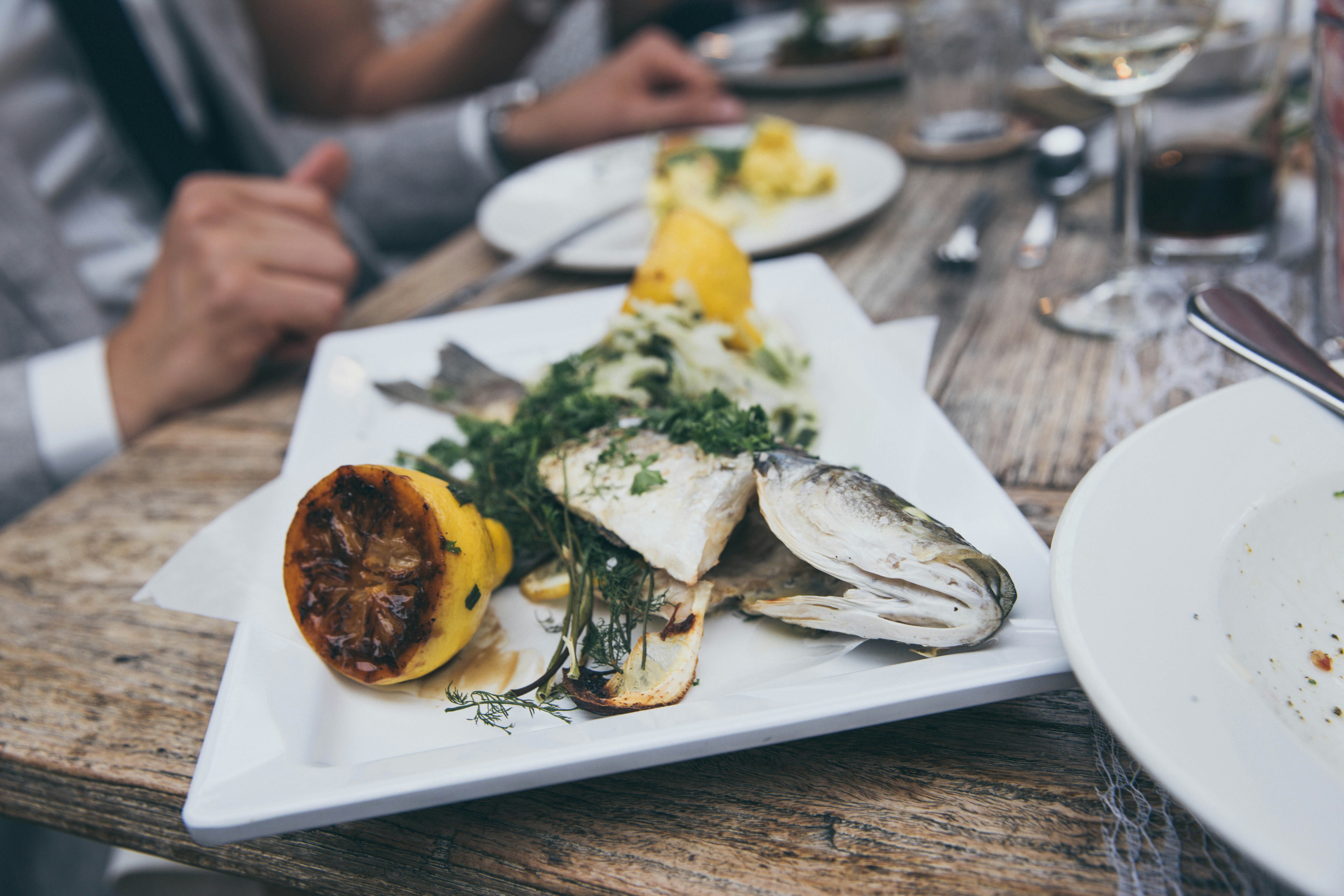 Et glas frisk hvidvin ved siden af en tallerken med grillet Fisch und Meeresfrüchten